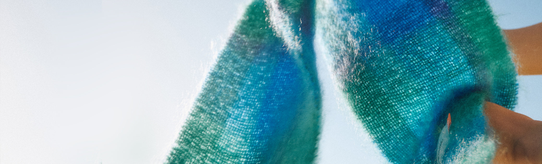 Blue and green tartan scarf flowing through the air against a light blue sky