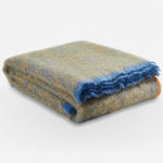 A neatly folded Ochre Clash Mohair Throw Blanket before packing it